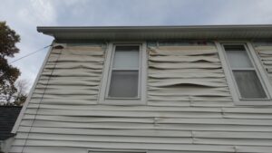 Here's an alt tag for the image: Damaged house siding needs repair.