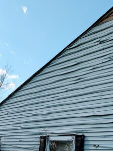 Here's an alt tag for the image: `Storm-damaged house siding needs repair.`