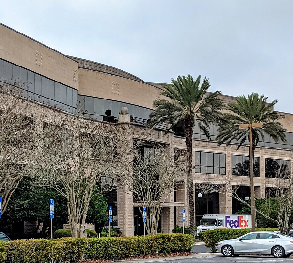 A building with palm trees and cars parked in front of it.